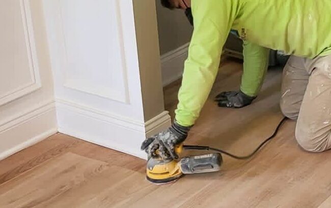 picture of man sanding hardwood floors and another man polishing them