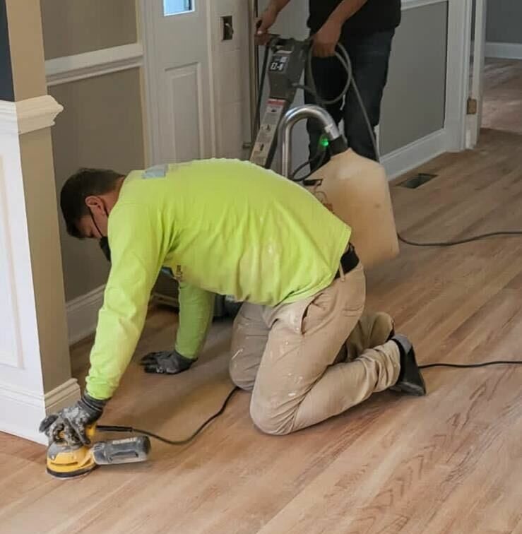 picture of two men sanding floors and polishing them by hand